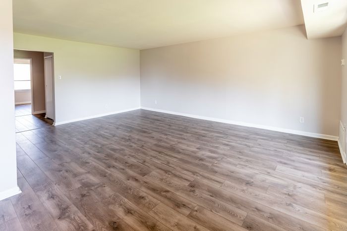 Spacious empty living room with wood-look flooring.