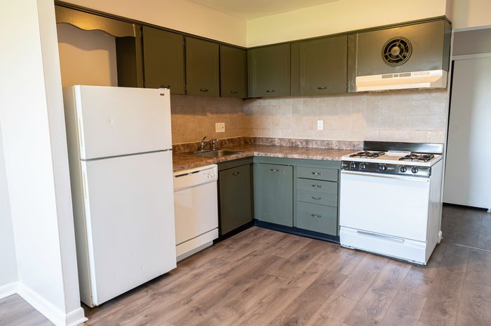 Kitchen with white appliances, gray cabinetry and laminate floors at Woodcrest Village Apartments