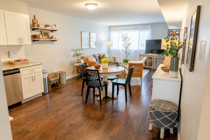 Open living and dining area at 405 at Main Apartments in Collegeville, PA with hardwood floors, round table, sofa, and TV.