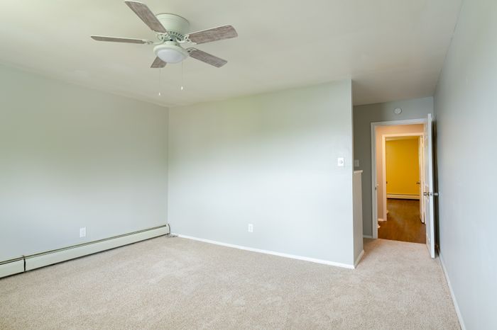 spacious carpeted bedroom with ceiling fan