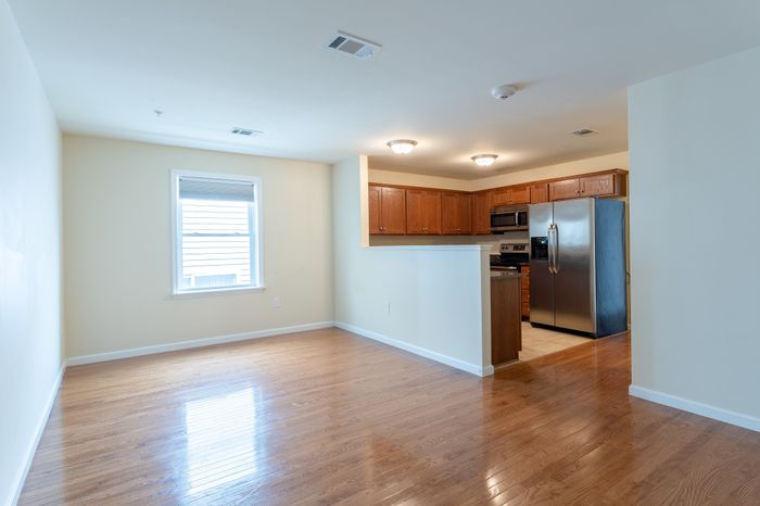 open room with window and wood floor facing kitchen