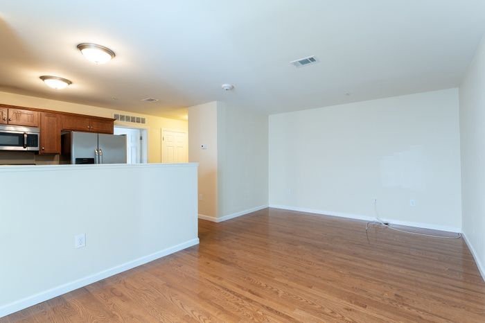 open room with wood floor and half wall to kitchen