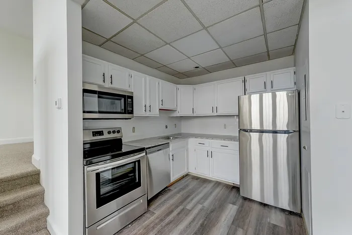 Kitchen at Franklin Manor Apartments in West Reading PA with white cabinets, black quartz counters and stainless appliances.