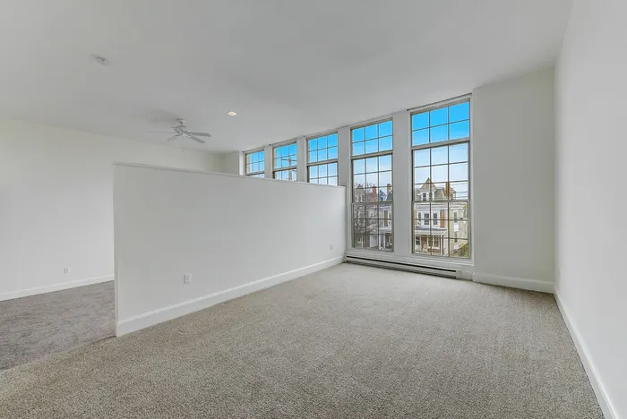 Empty bedroom with gray carpet and large windows at Franklin Manor.