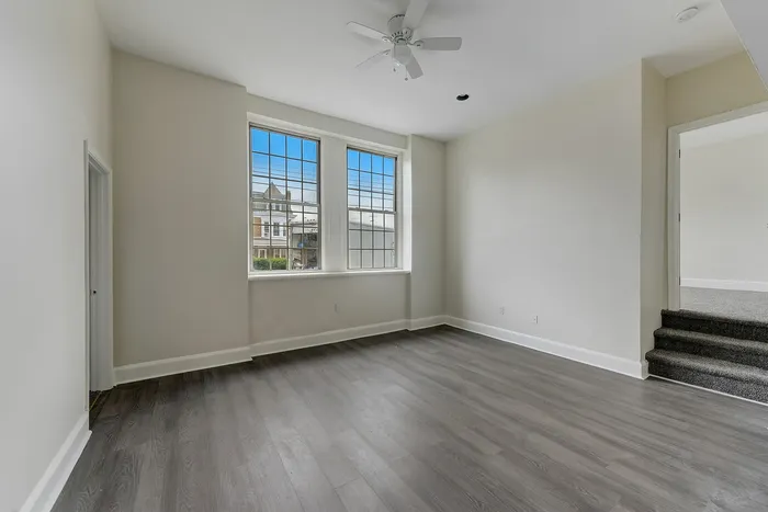 Bright empty apartment living room with hardwood floors and large windows at Franklin Manor Apartments.