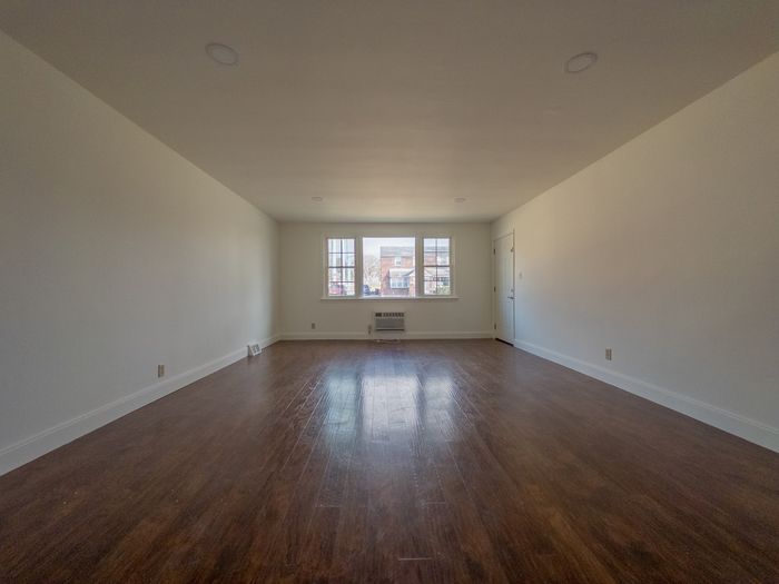 large living room with big window, wood floor and light walls