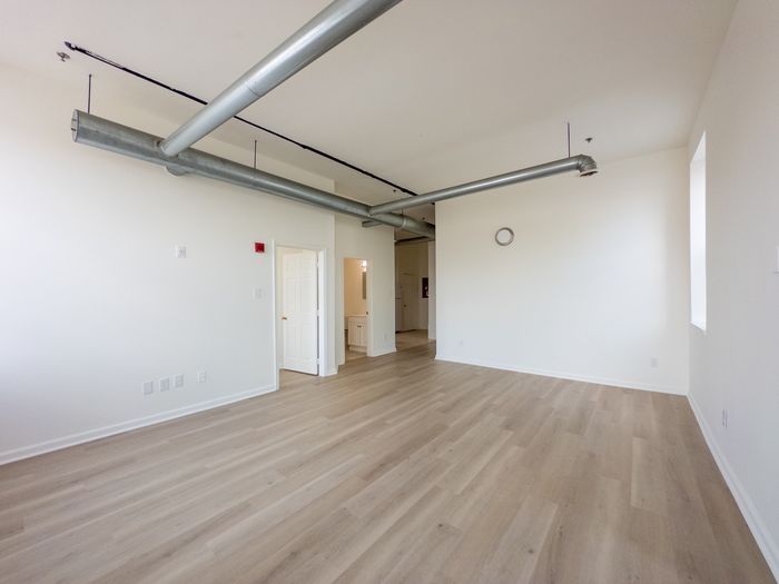 spacious living room with exposed air ducts, vinyl plank flooring