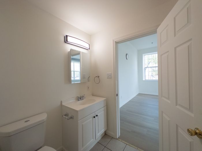 vivid white bathroom with vanity sink, doorway leading to living room