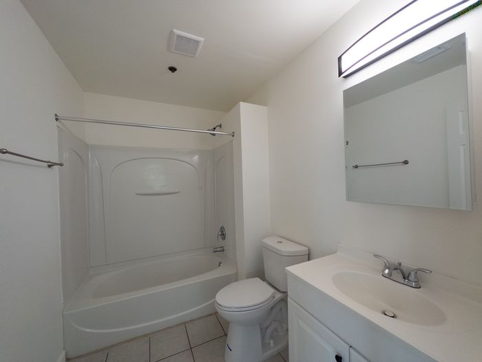 vivid white bathroom with vanity sink, toilet, tub/shower combo and tile floor