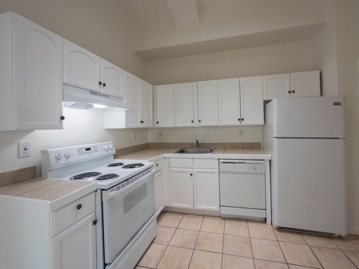 kitchen with white cabinets, tile floor, dishwasher, stove, range hood, and fridge