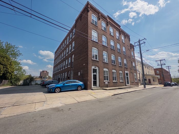 tall brick building with small attached parking lot, sidewalks lining the street