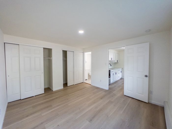 spacious bedroom with two closets, recessed lighting, doors leading to bathroom and kitchen