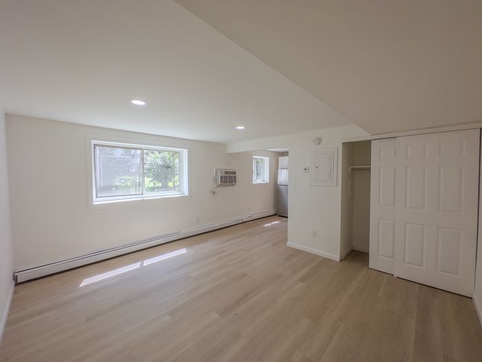spacious living room with closet and air conditioner, large windows, vinyl flooring