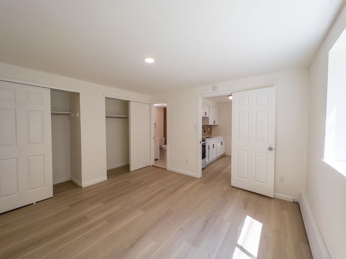bedroom with vinyl plank flooring, two closets, doors leading to bathroom and kitchen