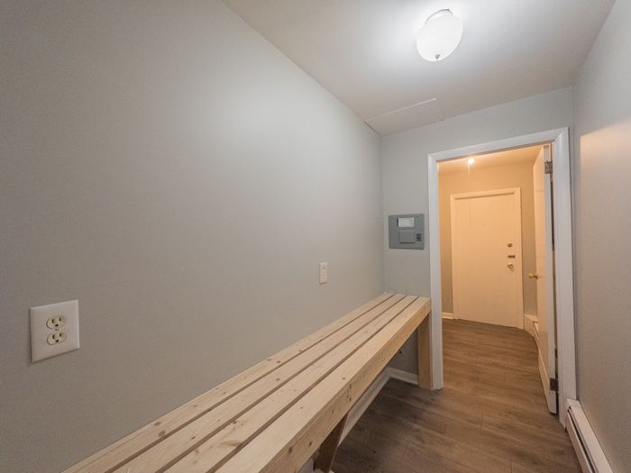 hallway with large storage shelf, door leading to hallway of building, bright lights