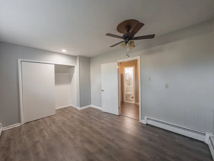 apartment bedroom with recessed light, ceiling fan with lights, sliding door closet, vinyl floor, doorway leading to kitchen and bathroom