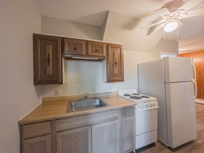 apartment kitchen, cabinets, refrigerator and range, ceiling fan with lights, wood cabinets