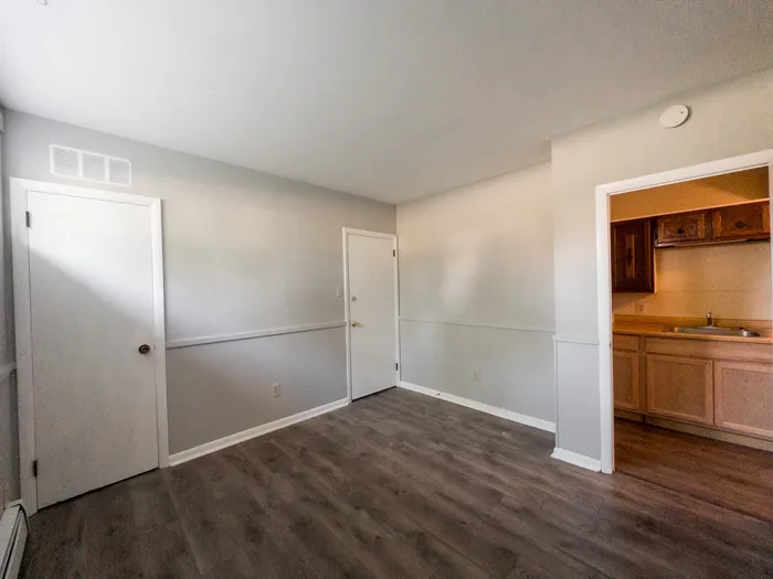 apartment living room with closet, doorway leading to kitchen, entrance door leading to building hallway
