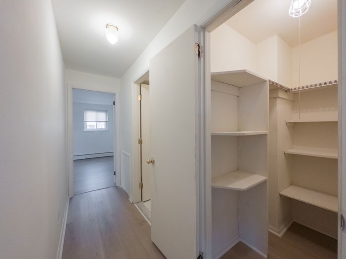 hallway with doors to bedroom and bathroom, view into large walk-in closet with lots of shelves