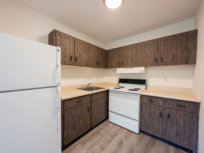 The Cloverleaf apartments in Laureldale, PA kitchen with wood-grain cabinets, white refrigerator and a stove.