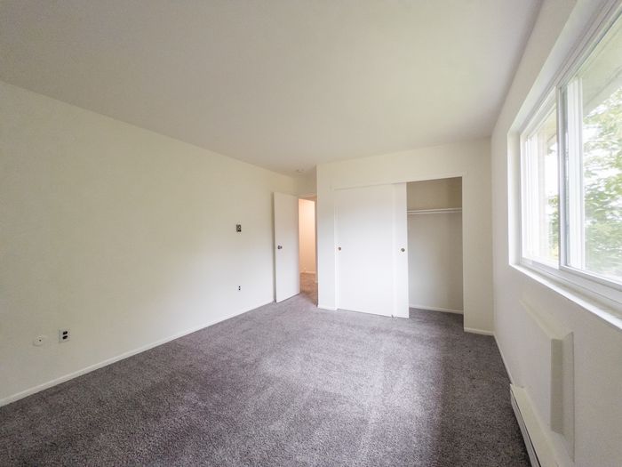 Spacious bedroom with a closet and a window at The Cloverleaf Apartments.