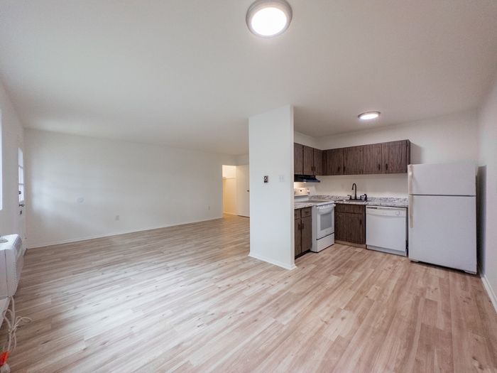 Open living room and kitchen at The Cloverleaf apartments in Laureldale, PA with wood-look floors and appliances.
