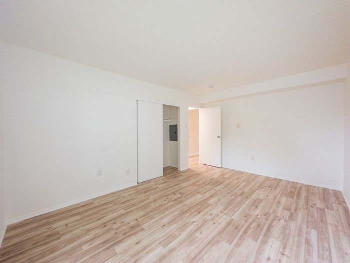 Spacious empty bedroom with wood-look floors and closet at The Cloverleaf.