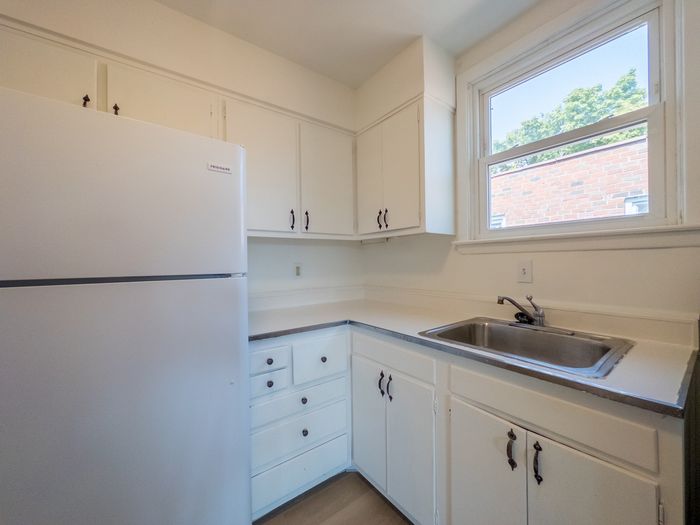 kitchen with refrigerator, window over sink, new range, lots of cabinets, white cabinets, wood flooring