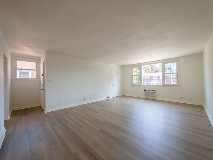 spacious apartment living room, large windows, wood flooring, storage closet, renovated apartment
