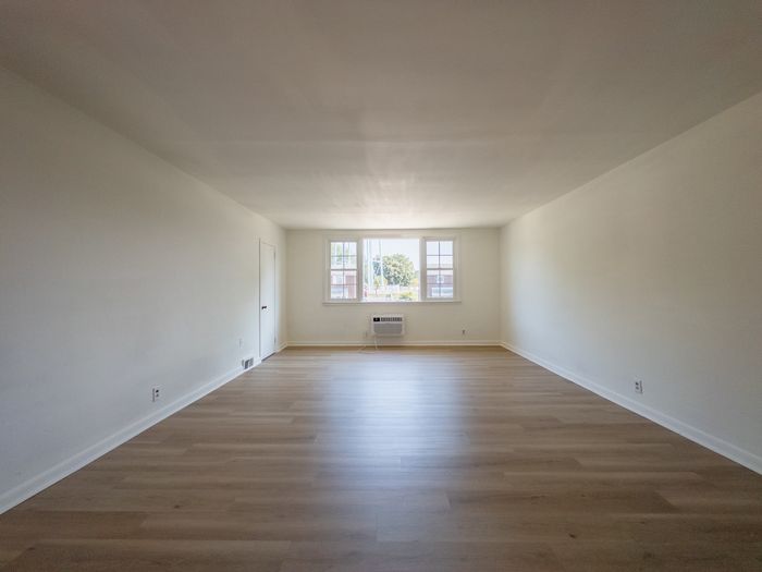 spacious apartment living room, large windows, wood flooring, storage closet, renovated apartment