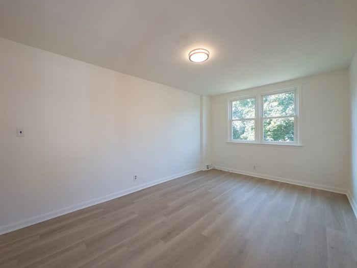 renovated apartment bedroom, large window, overhead light, wood flooring