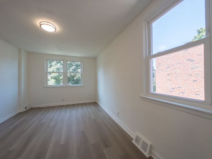 renovated apartment bedroom, large window, overhead light, wood flooring