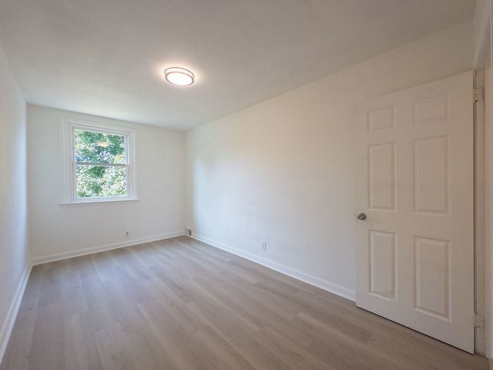 renovated apartment bedroom, large window, overhead light, wood flooring