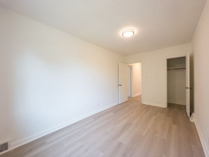 renovated apartment bedroom, large window, overhead light, wood flooring, closet