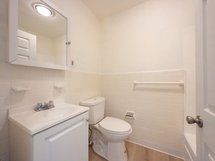 renovated apartment bathroom, vanity sink, medicine cabinet, tiled wall, energy efficient toilet