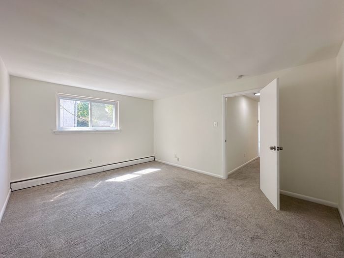 apartment bedroom with carpet floor, window, door leading to hallway