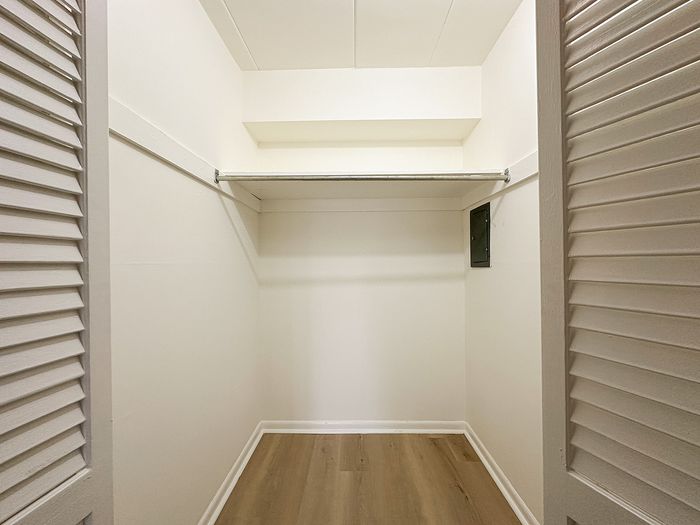 Spacious walk-in closet with elegant wood flooring and ample shelving for storage solutions.