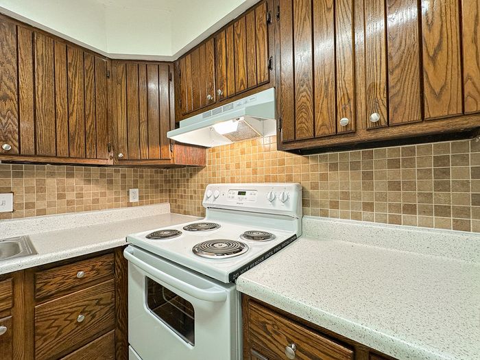 Charming kitchen featuring rustic wooden cabinets, modern stovetop, and sleek countertops with a warm, inviting atmosphere.
