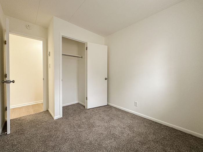 Bright and inviting bedroom with plush carpet, fresh white walls, and a built-in closet. Perfect for restful living and personal style expression.