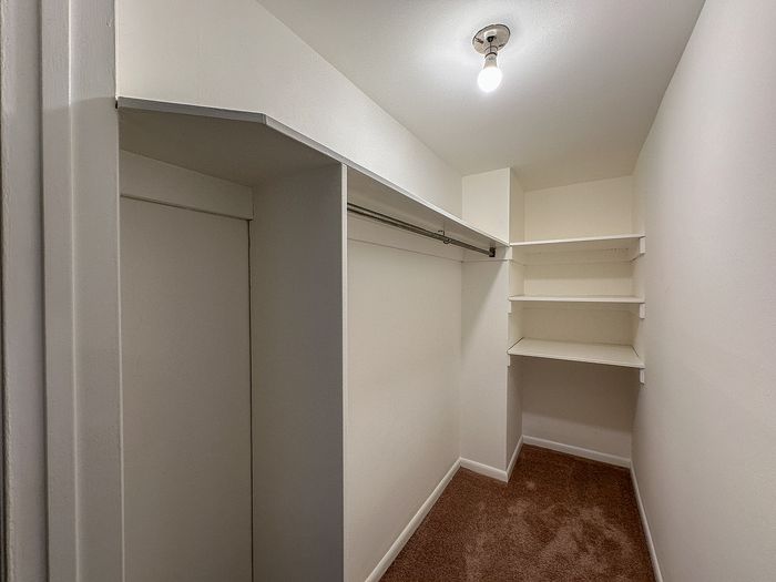 Spacious walk-in closet with ample shelving and hanging space, perfect for organized storage.