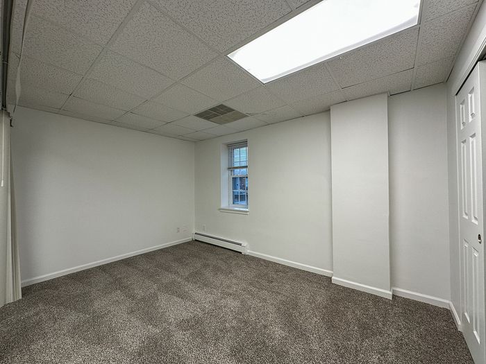 Spacious room with new carpet flooring, fresh paint, and a bright window creating a warm, inviting atmosphere.