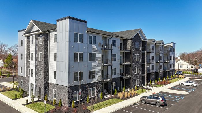 Modern four-story apartment building with stylish facade, featuring multiple balconies and ample parking in a vibrant neighborhood. The warrington place apartments in warrington pa