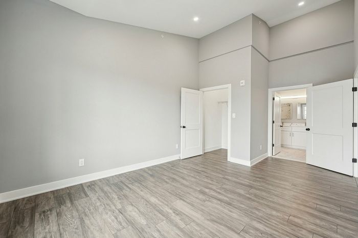 Bright, spacious room with elegant wood flooring, high ceilings, and double doors leading to a contemporary bathroom.