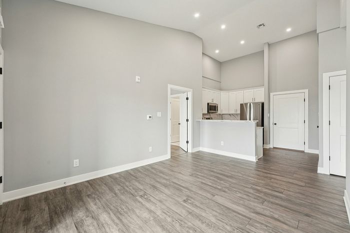 Bright and modern open-concept apartment with sleek hardwood floors, elegant kitchen with stainless steel appliances, and high ceilings.