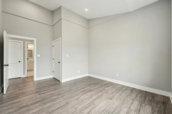 Bright and spacious room with elegant hardwood flooring and modern light gray walls, perfect for a stylish bedroom or home office.