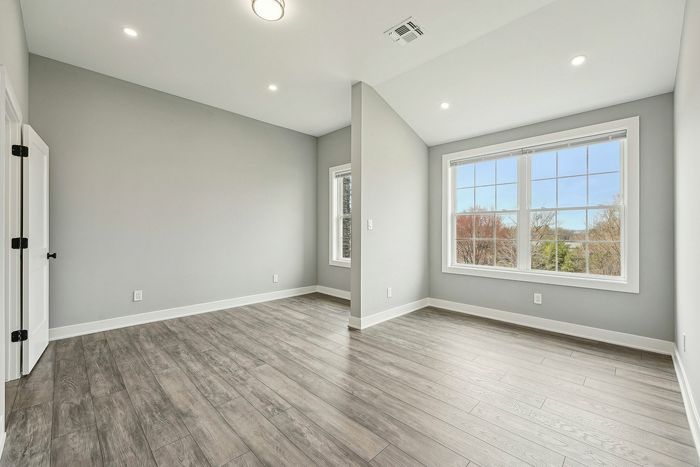 Bright and airy room with modern wood flooring and large windows offering a scenic view.