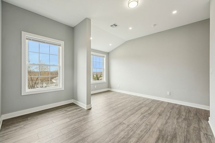 Bright, airy room with large windows and elegant hardwood flooring, perfect for creating a cozy living space.