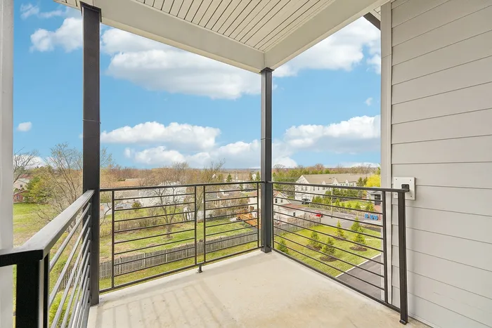 Refreshing apartment balcony with modern railing offering stunning panoramic views of a vibrant neighborhood under a pristine blue sky.
