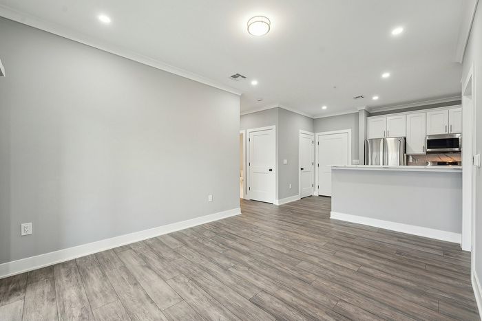 Modern open-concept apartment interior with stylish wood flooring, sleek kitchen finishes, and ample natural light.