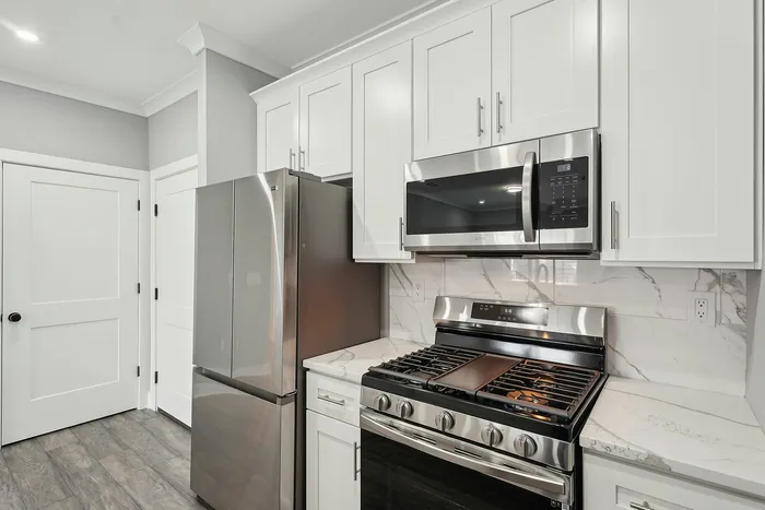 Modern kitchen with sleek stainless steel appliances, white cabinetry, and elegant marble countertops.